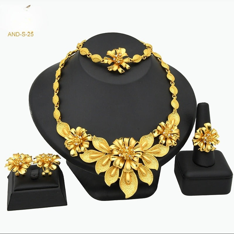 Gold-tone four-piece jewelry set with floral-link collar necklace, matching earrings, bracelet, and ring