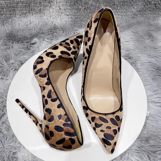 Leopard print high-heeled shoes on a white platform with a gray textured background