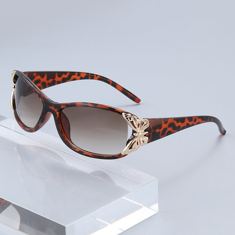 Tortoiseshell driving sunglasses with dark gradient lenses and gold-tone emblem front