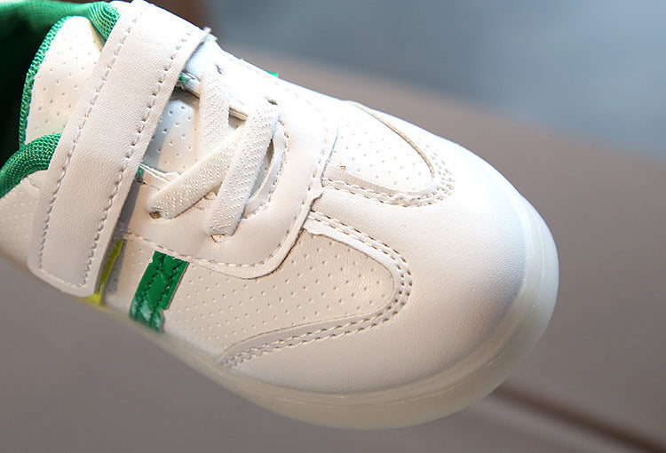 Kids white LED light-up sneaker side with green strap detail; textured upper view