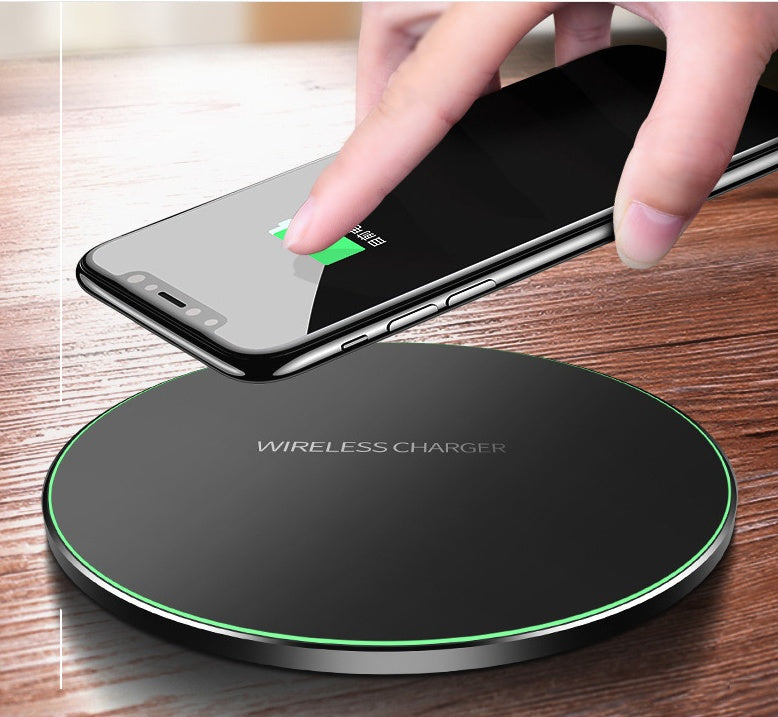 Black wireless charging pad with green LED ring and phone being placed on it