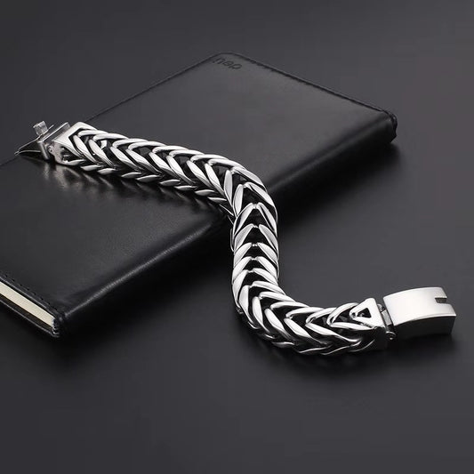 Silver braided bracelet on a black surface with a black notebook
