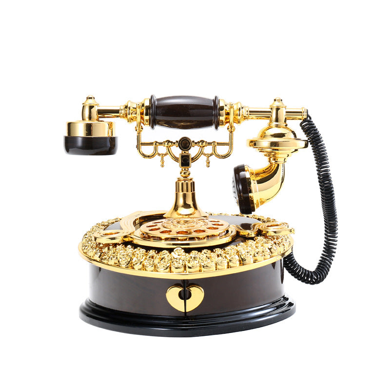 Ornate retro rotary desk telephone with gold finish, dark base, rotary dial and coiled cord