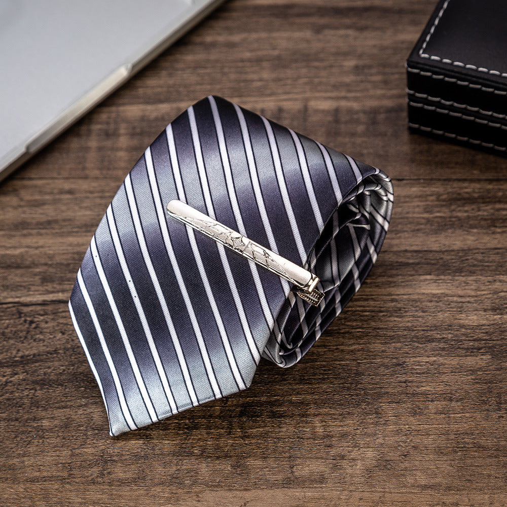 Men's striped necktie with tie bar, folded on wood surface.