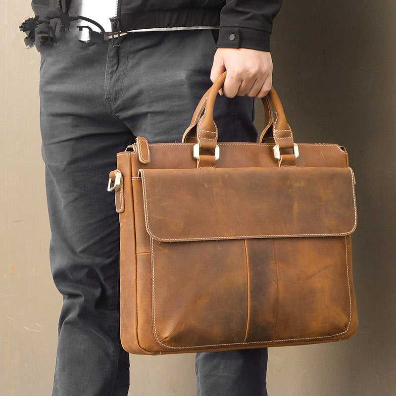 Brown leather crossbody bag held by top handle, flap front with stitched edges.