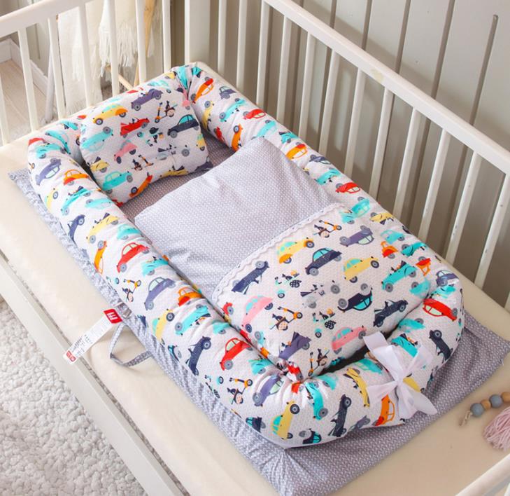 Portable baby nest crib with light blue vehicle print mattress and bolster pillow set