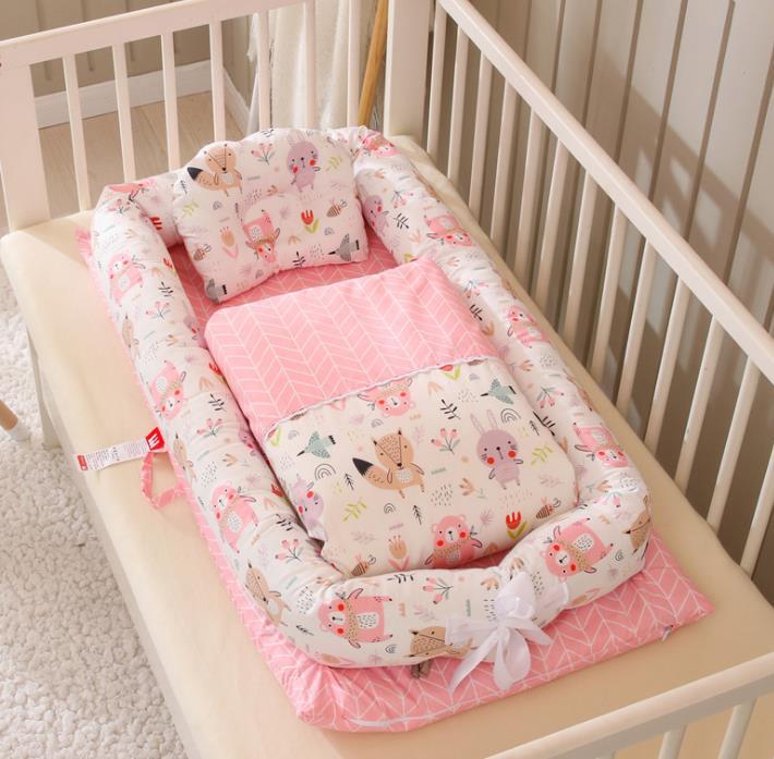 Portable baby nest crib with pink woodland animal print mattress and bolster pillows