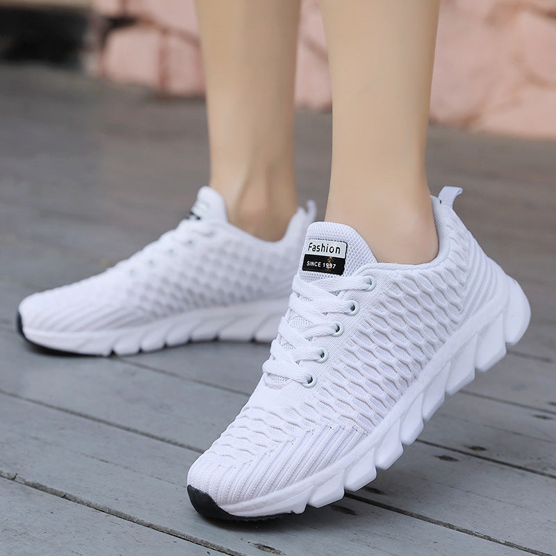 White knit running shoes with lace-up front and thick cushioned sole