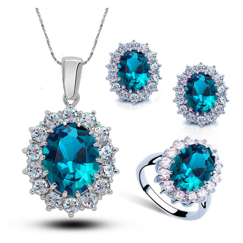 Crystal bridal jewelry set with blue gemstone necklace, earrings, and ring in silver tone.