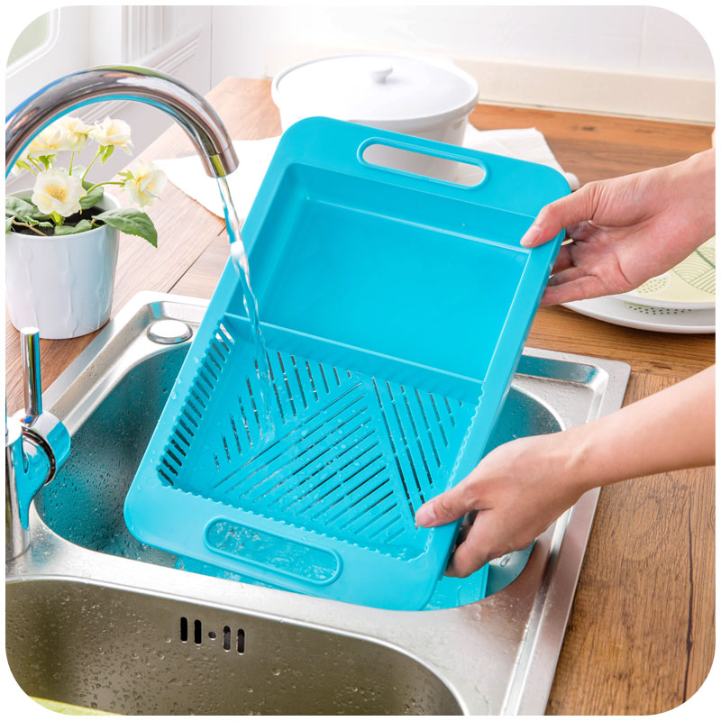 Blue multifunction chopping board in a sink, draining through the textured strainer base
