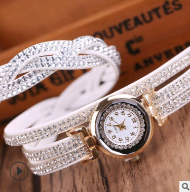 Luxury watch with white strap and gold accents on a wooden surface