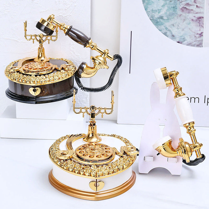 Ornate retro desk telephone with gold accents, dark base, rotary dial and coiled cord