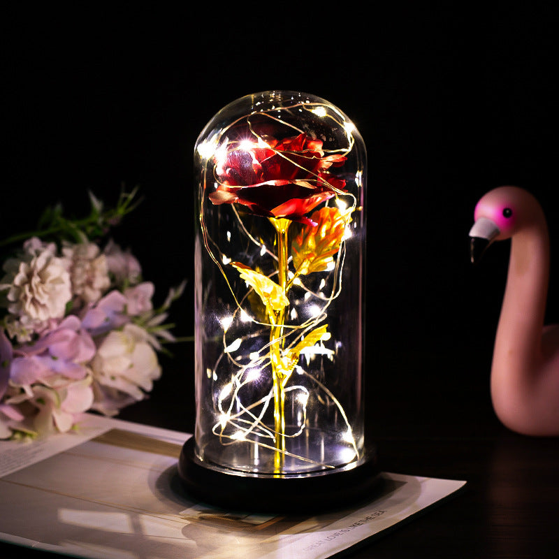 LED rose glass dome light with red rose, warm string lights, black base.