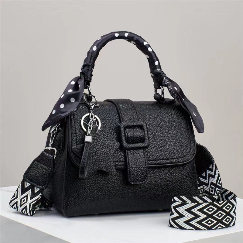 Black handbag with top flap, front buckle detail, and patterned chevron strap accents