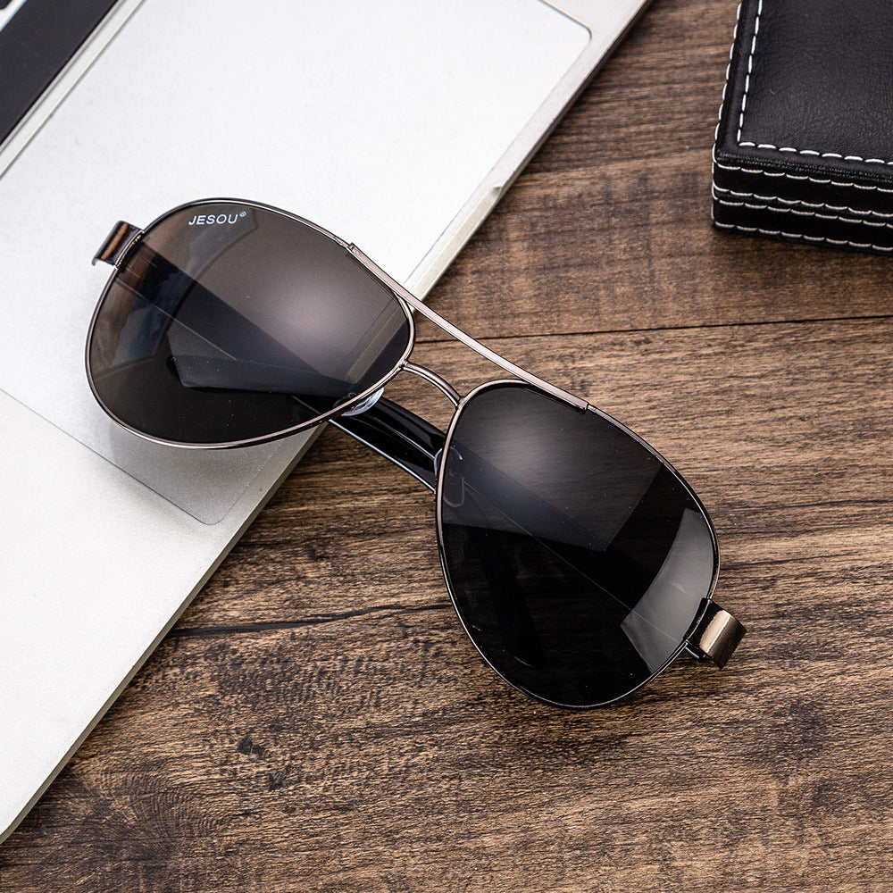 Men's aviator sunglasses with dark lenses and silver frame on notebook and card.