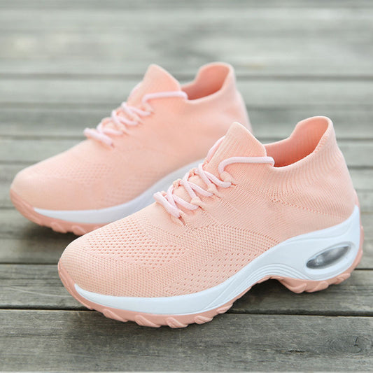 Pair of pink sneakers with white soles on a wooden surface