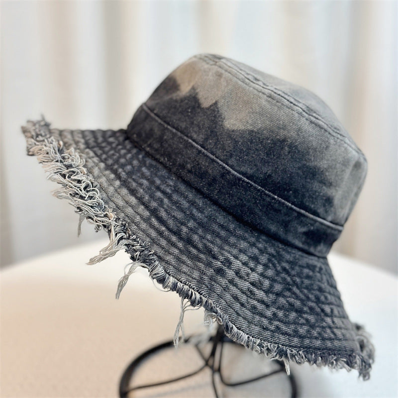 Dark wash denim bucket hat with frayed wide brim and curved seam lines