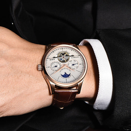 Luxury wristwatch with detailed face on a person's wrist, wearing a suit.
