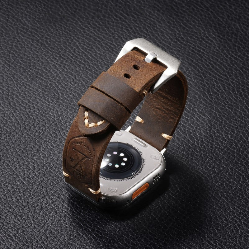 Brown leather watch strap worn on a watch, with perforations and silver metal clasp