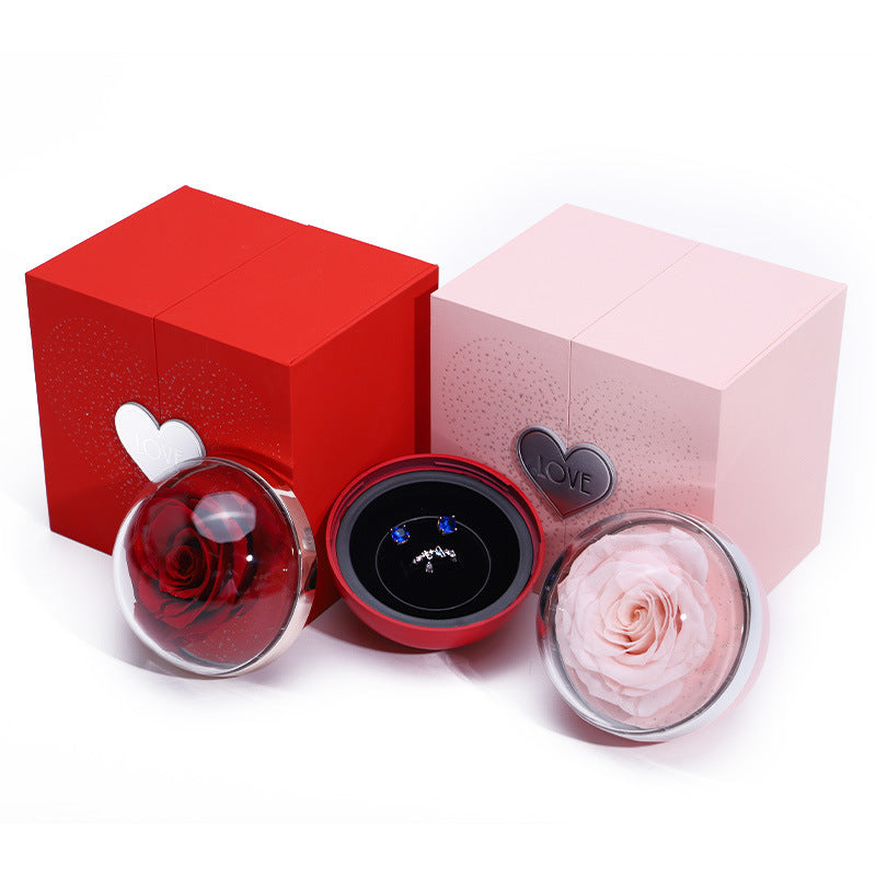 Red and pink gift boxes with clear domes holding roses and heart-shaped ornament