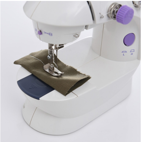 Close-up of sewing needle stitching olive fabric on machine bed