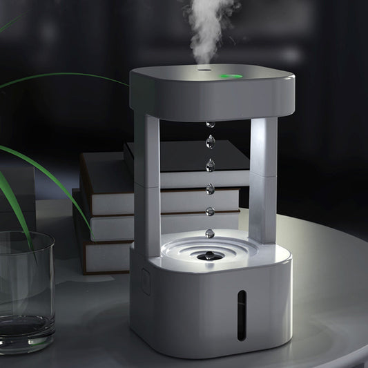Humidifier emitting mist on a dark background with books and a glass.
