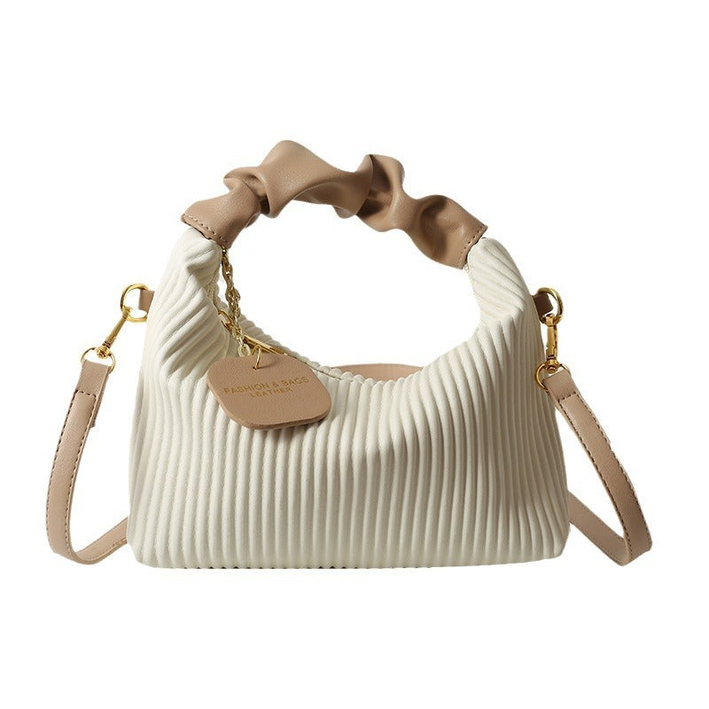 Cream ribbed PU leather crossbody bag with gathered top, gold hardware, and charm tag
