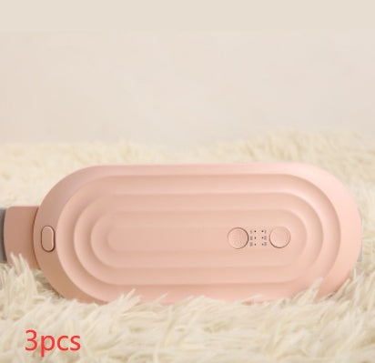 Pink electric waist massager belt lying on plush fabric, control area and buttons visible.