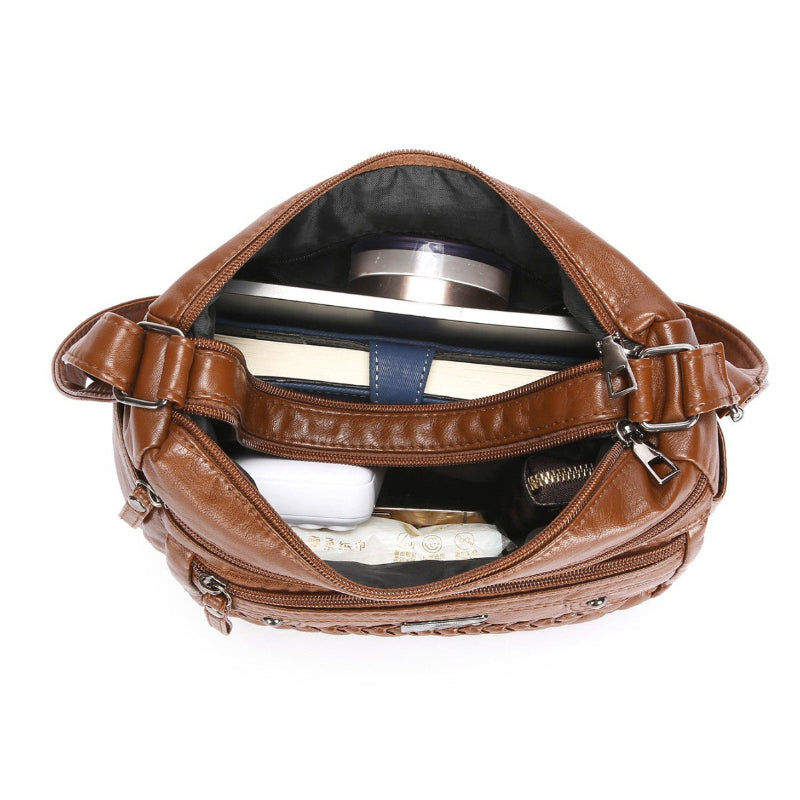 Tan leather shoulder bag with open top lining view, adjustable strap, and inner compartment