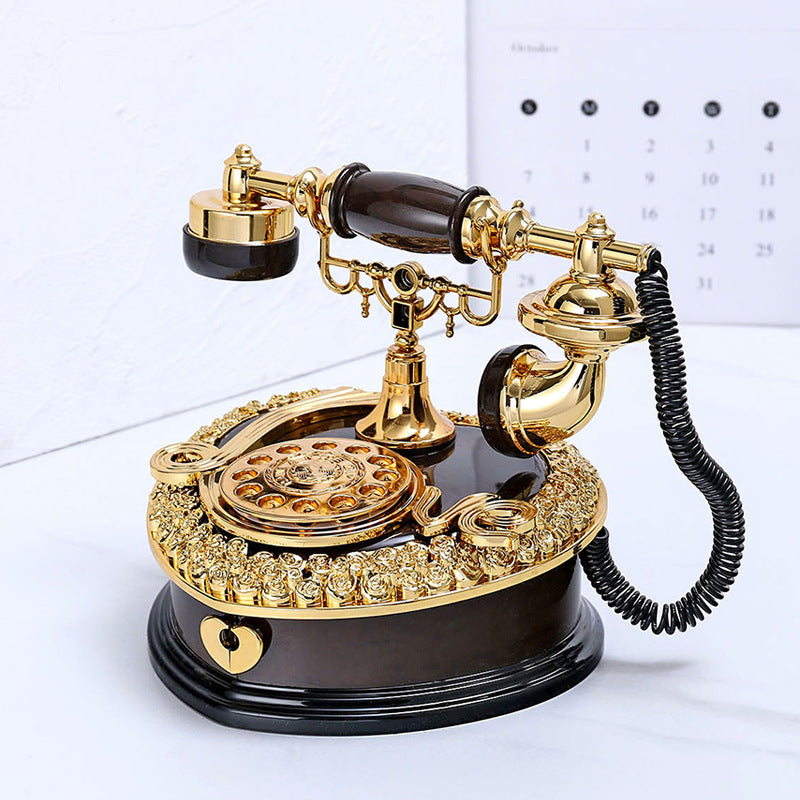 Retro rotary desk telephone in gold and dark, ornate cradle, rotary dial, black cord