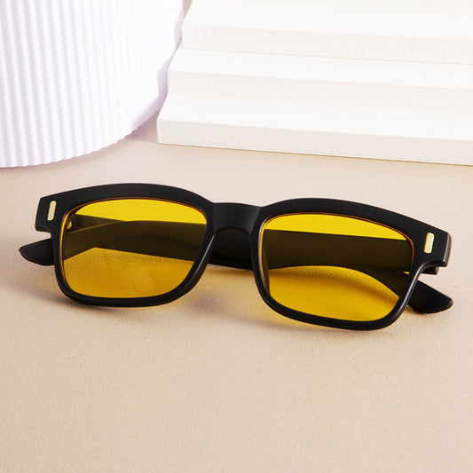 Sunglasses with yellow lenses and black frames on a beige surface