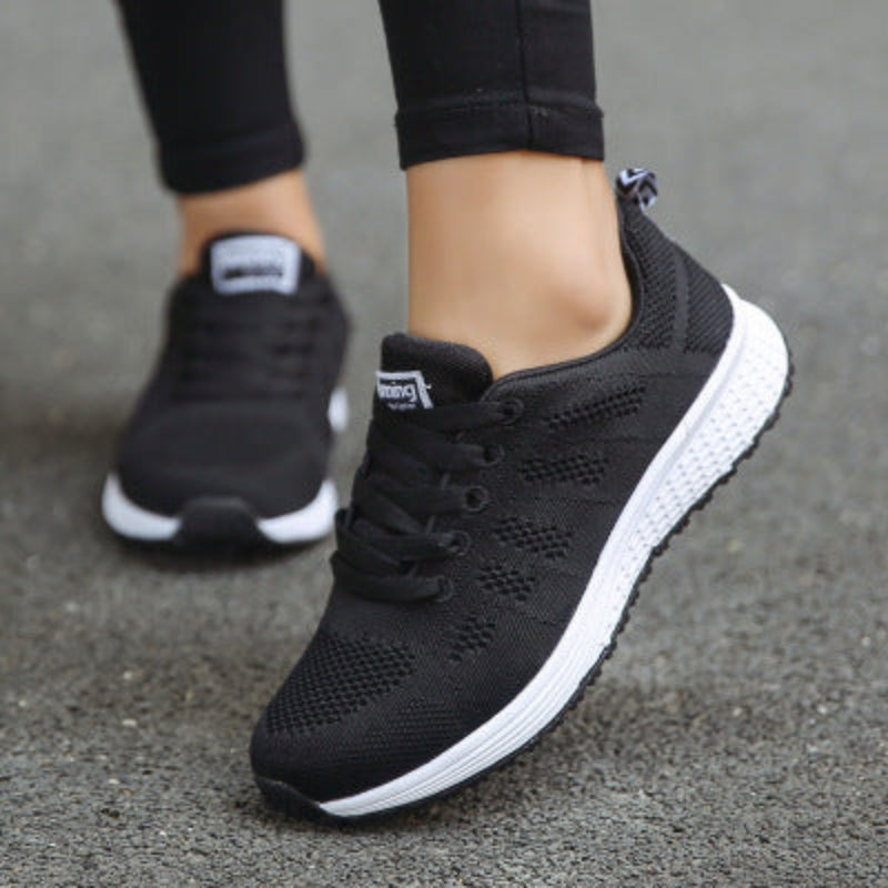 Women’s mesh sneakers, black upper with white rubber outsole worn with dark pants