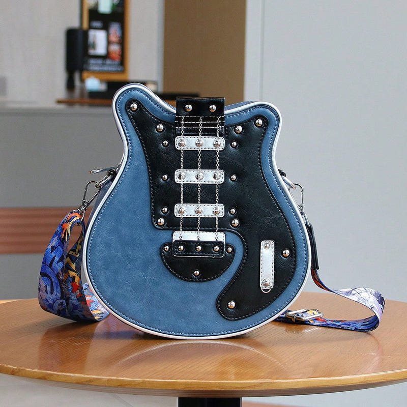 Guitar-shaped crossbody bag with blue front, black hardware, and patterned guitar strap