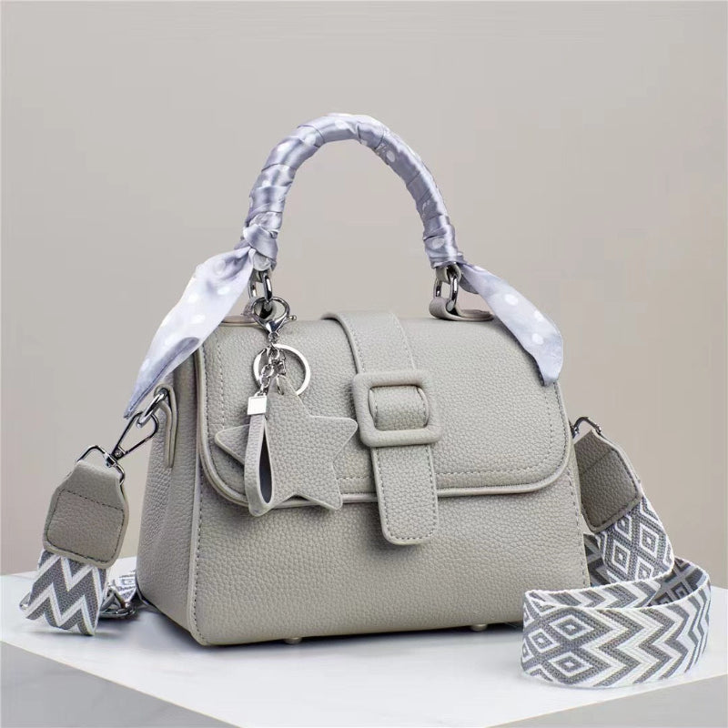 Cream handbag with top flap, front buckle detail, and patterned chevron strap accents