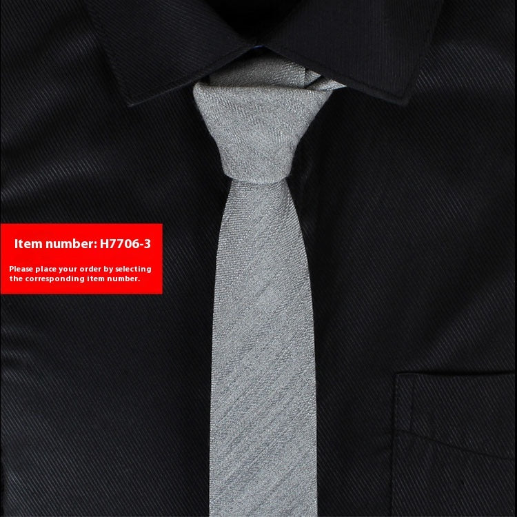 Narrow cotton tie in light gray textured weave, slim knot.