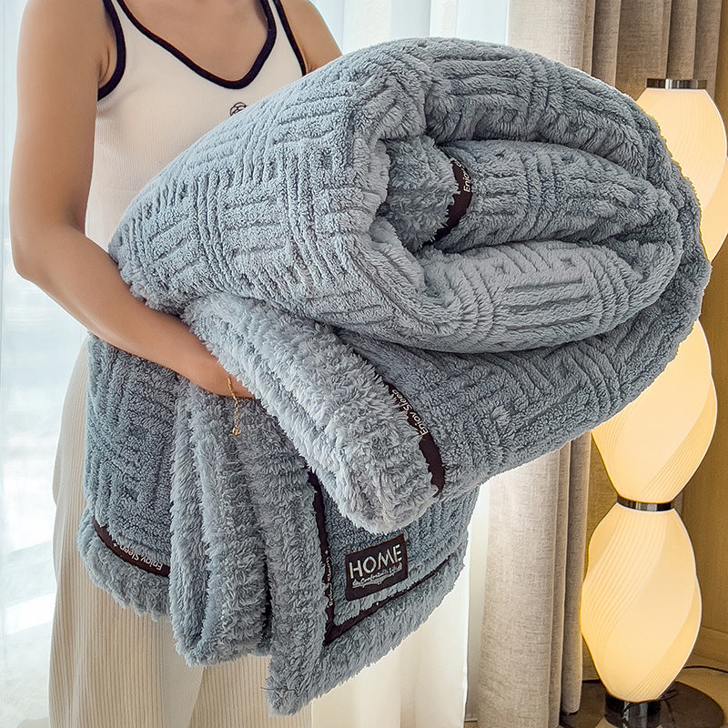 Plush velvet winter blanket in slate gray with dark striped trim and small logo label