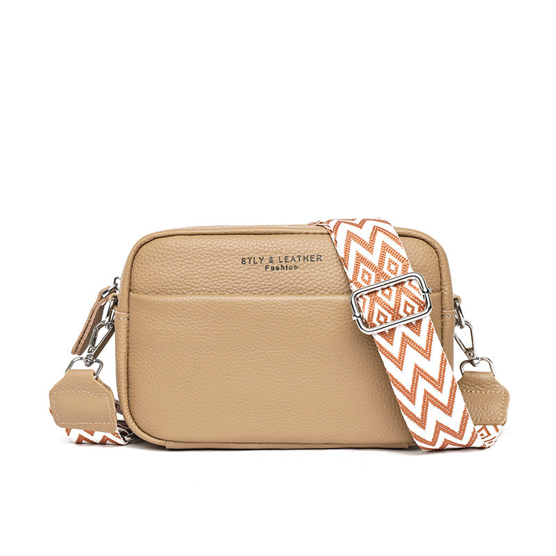 Beige crossbody bag with zip-top closure, chevron strap, and silver-tone hardware