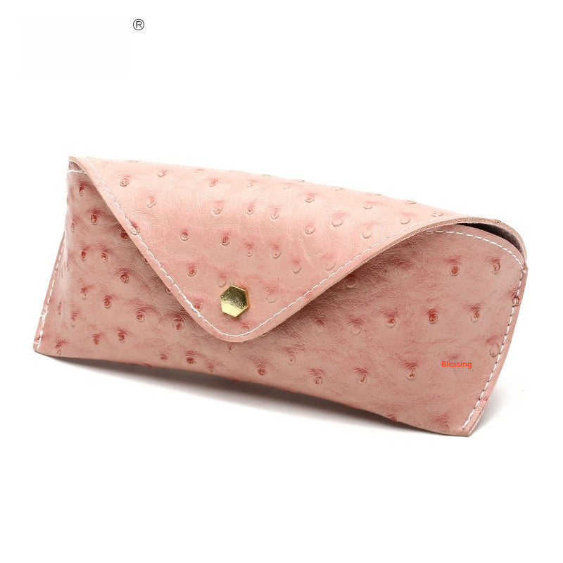 Pink polka dot leather sunglasses case with curved flap and gold-tone clasp, stitched edges