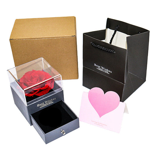 Gift set with a rose in a box, a black bag, and a pink heart card on a white background.