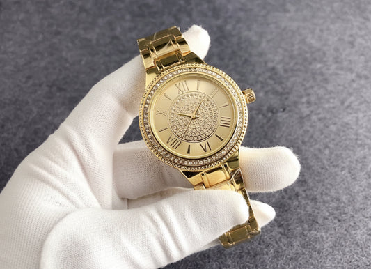 Gold watch held by a hand with Guess packaging in the background