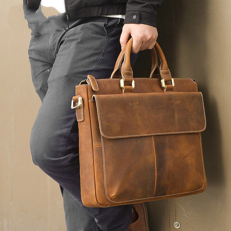 Brown leather crossbody bag with top handle, flap front, and stitched trim.