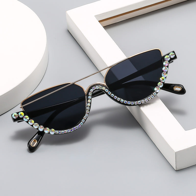 Cat-eye sunglasses with dark lenses, gold arms, and multicolor rhinestone detailing at edges
