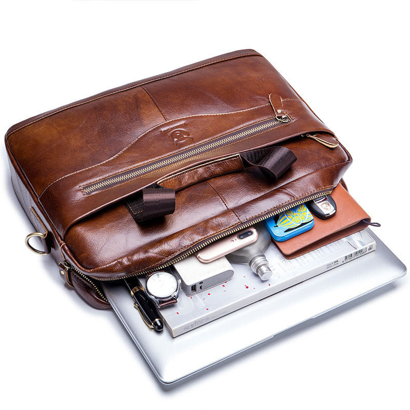 Brown leather briefcase laid open, showing zipper compartment and items inside