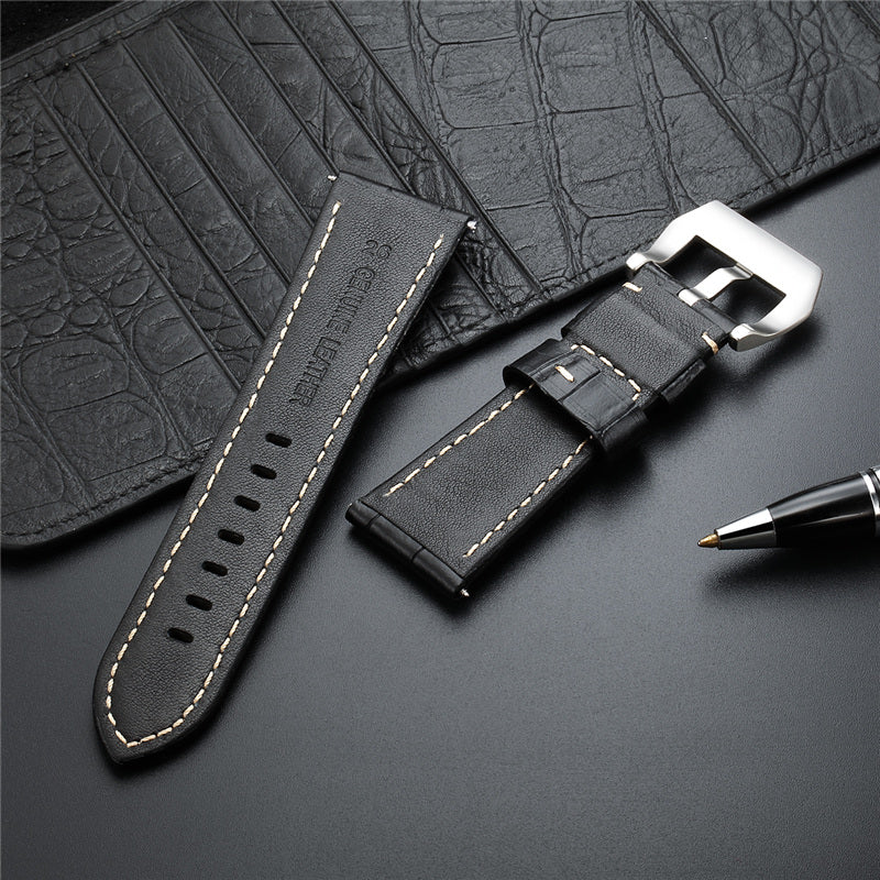 Black leather watch strap with metal buckle, perforations, and tan stitching.