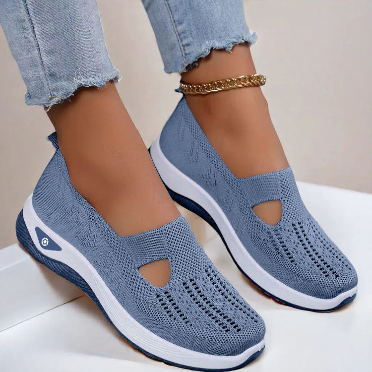 Women's Blue slip-on shoes with white soles worn with light blue jeans on a neutral background