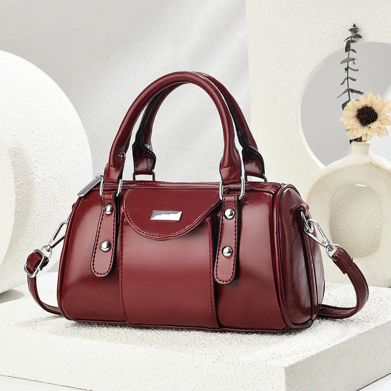 Purplish red glossy PU shoulder handbag with top handles and crossbody strap