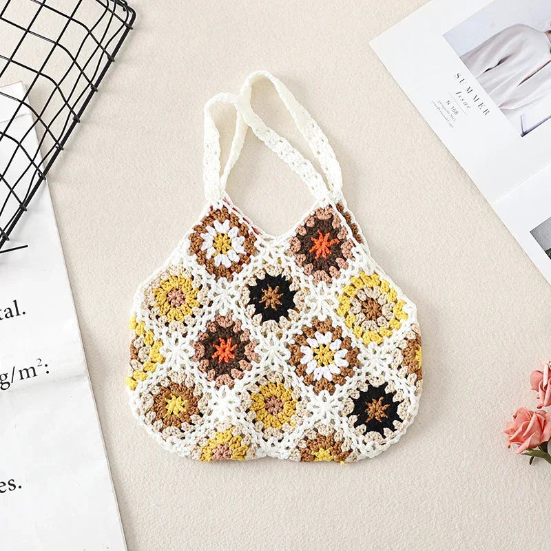 Crochet wool handbag tote with cream base, multicolor floral granny squares, and white handles.