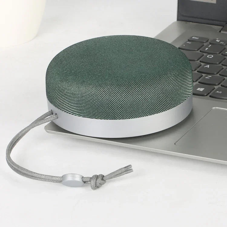 Green cloth-covered Bluetooth speaker with hanging cord and silver base ring