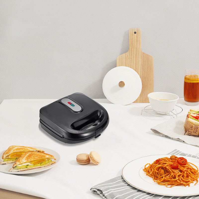 Black electric sandwich maker with indicator light, placed on kitchen counter