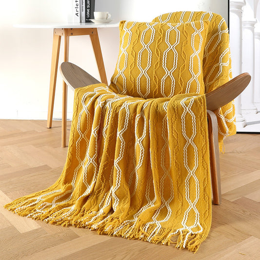 Yellow textured blanket draped over a wooden chair on a wooden floor.